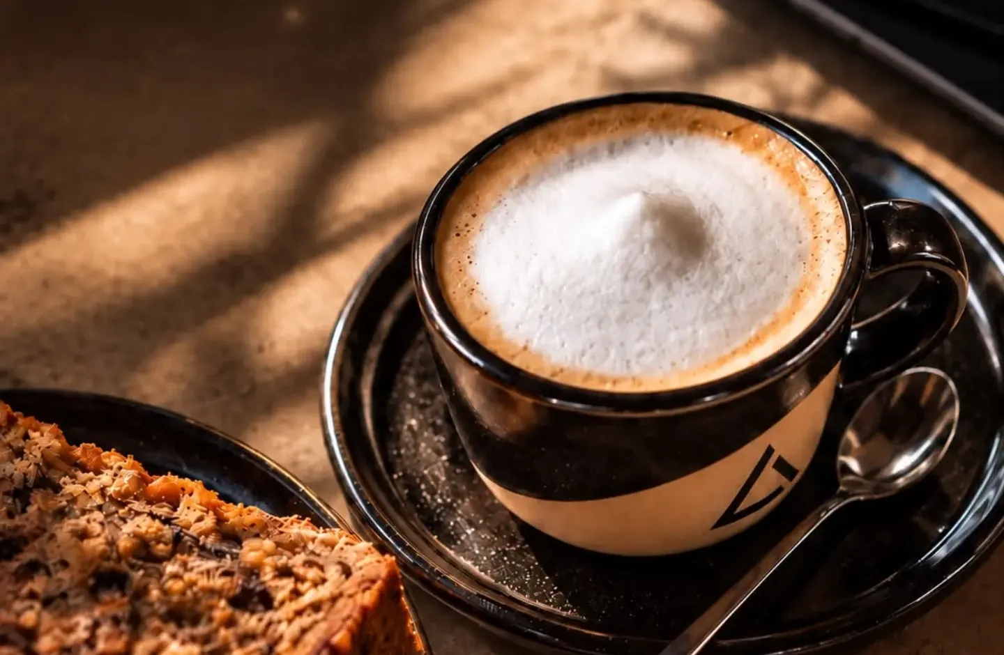 Café con leche en una taza con el triángulo de Refugio, al sol de la mañana